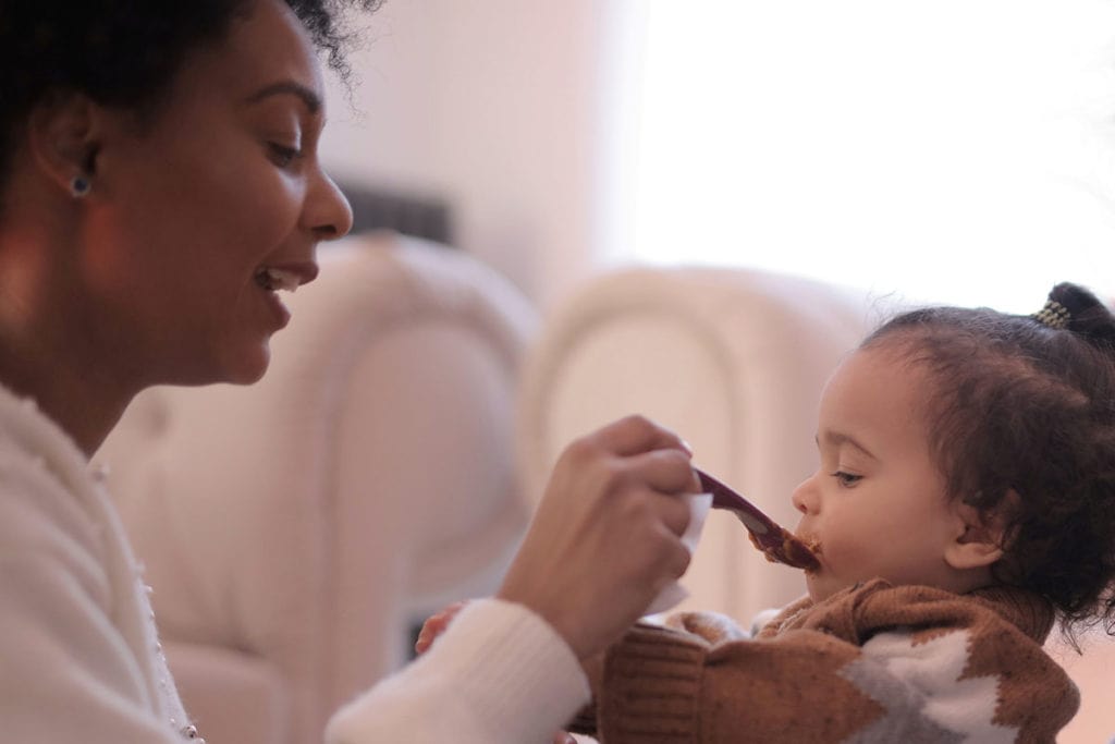 A woman feeding her very young child